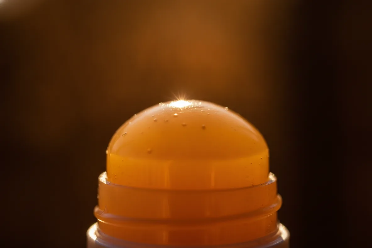 Makroaufnahme der glänzenden Kuppe eines Lippenpflegestifts im Sonnenlicht